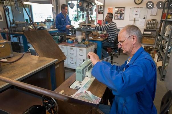 Vrijwilliger repareert naaimachine in werkplaats Tools To Work